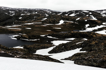 Typical norwegian landscape with snowy mountains and clear lake near the famous Aurlandsvegen (Bjorgavegen), mountain road, Aurland, Norway.