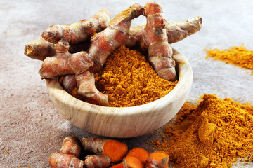 Turmeric powder and fresh turmeric on grey background