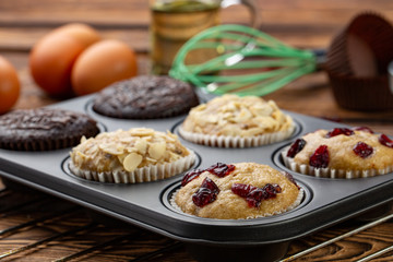 Different Muffins in bakeware or muffin pan on broun wooden background. Basic muffin recipe. Homemade muffins for breakfast or dessert.
