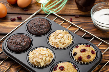Different Muffins in bakeware or muffin pan on broun wooden background. Basic muffin recipe. Homemade muffins for breakfast or dessert.