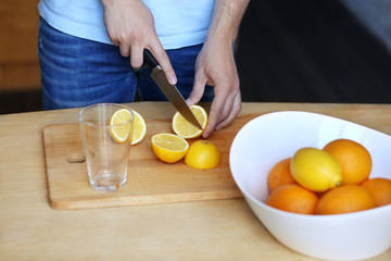 Obraz na płótnie Canvas Preparation of lemonade,hand with a knife cutting lemon on wooden board.