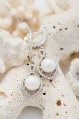 Fototapeta na wymiar Silver earring with pearl and diamonds on coral
