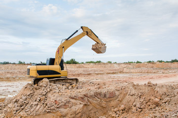 Fototapeta na wymiar Yellow excavator machine working earth moving works at construction site