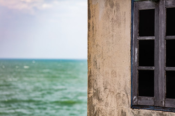 old stone house with wooden window with sea background