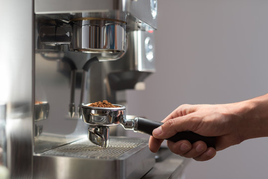 Woman's hand holding portafilter recipient filled with coffee ground