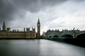 Panoramic long exposure of The Houses of Parliament, the Big Ben and Westminster Bridge in London silhouetted against  thick dark clouds