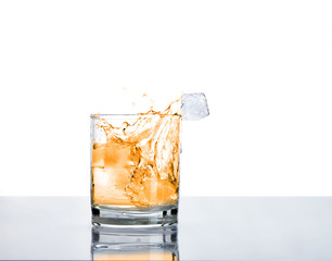 Glass of alcohol with ice and splashes