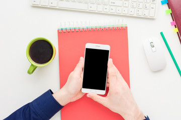 white desktop, white desk, male hands, guy uses white smart phone,  Notepad, background with copy space, for advertisement, top view