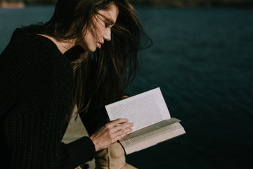 Obraz premium Young woman reading by the seaside