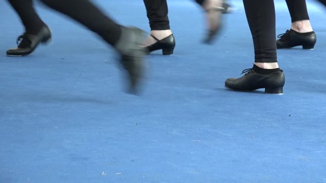 Girls feet&nbsp;tapping on blue carpet, tap dance Broadway style, stage at theatre. Tappers striking on blue background with shiny light. Learning musical culture, choreography at performance