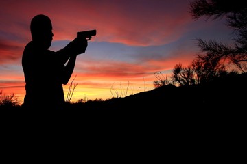 Silhouette of a man holding a firearm.