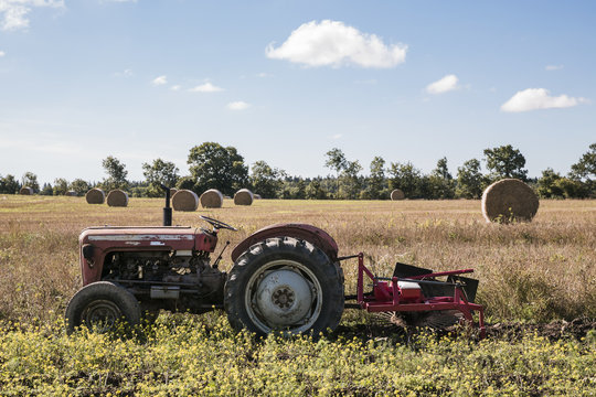 Old tractor in a field next to haystacks