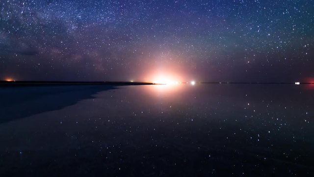 Night sky of stars and Milky way time lapse over the salt lake Elton. Milky way Galaxy and stars above the lake Elton and their reflection on water surface during an entire night.