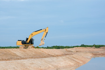 Fototapeta na wymiar Yellow excavator machine working earth moving works riverside at construction site