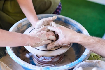 The master helps the student to make a pot of clay. Pottery wheel. Workshop of art therapy. Female...