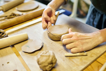 Pottery. A girl with a string in her hands cuts the top layer off clod clay. The process of modeling ceramic ware.