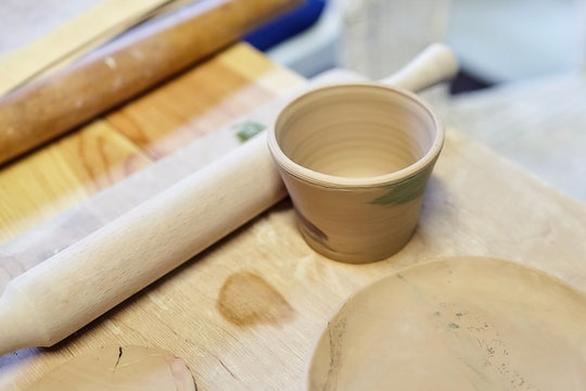Premium Photo  Earthenware ceramic products from raw clay mug stack  rolling pin lying on a wooden table art therapy