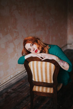 portrait os a ginger woman sitting on a chair in a empty room