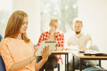 Student girl with tablet in front of her classmates