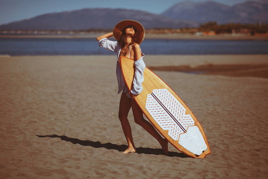 Young woman with a surf board on the beach