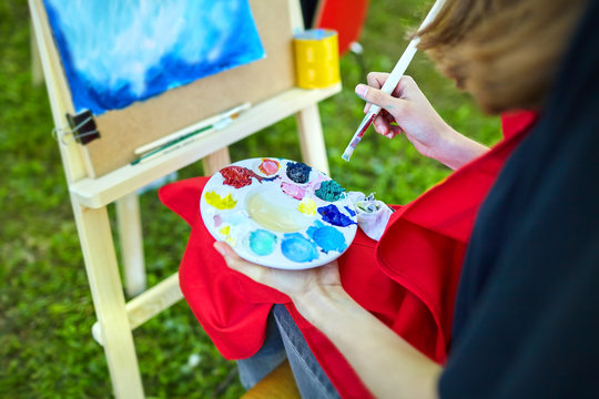 paints, brush, palette, female hand of the artist