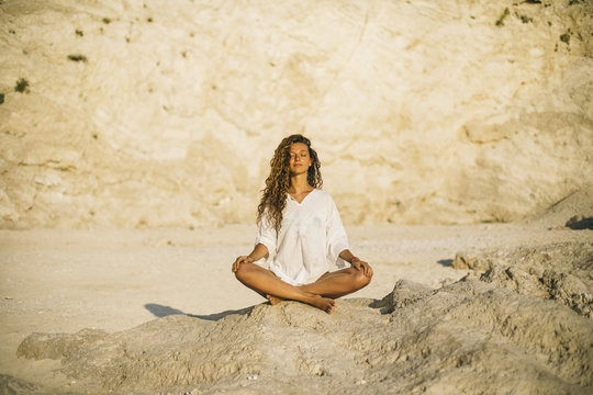 Young woman practicing yoga at the beach, by sunrise