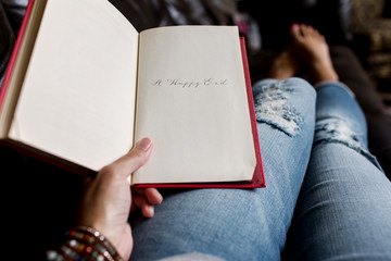 woman holding a book with ""A Happy End"" written on the last page
