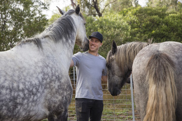 A man petting two horses at a farm