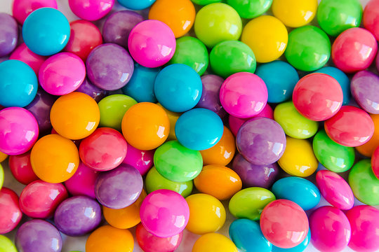 Pile of colorful sweet candy chocolates coated on white paper. colourful collection background