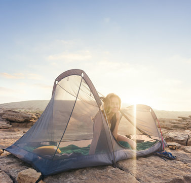 Beautiful woman relaxing in translucent tent in the golden hour