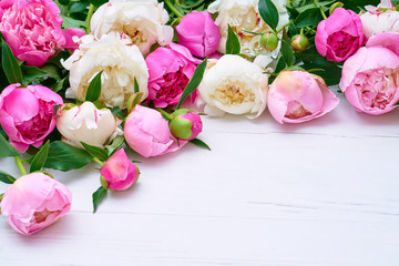 White and pink peonies on white wooden table. Holiday background, copy space, top view