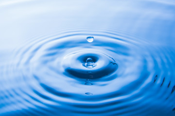 Water drop falling into water make waves. Water splash or water drop background.