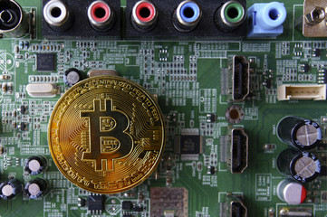 Gold souvenir coin Bitcoin on a computer circuit board background.