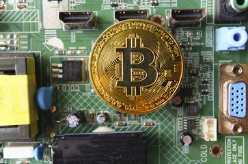 Gold souvenir coin Bitcoin on a computer circuit board background.