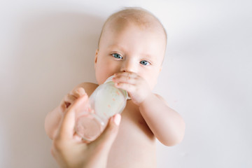 A portrait of cute newborn baby being fed by her mother using bottle