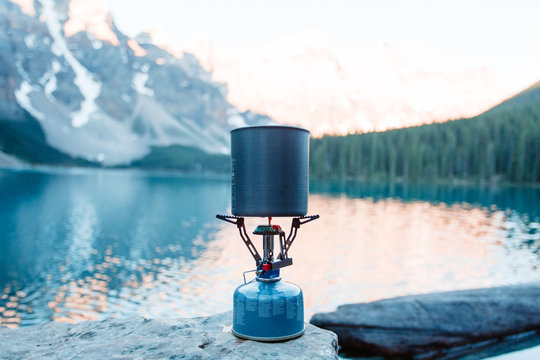 Boiling water with backpacking stove at mountain lake.