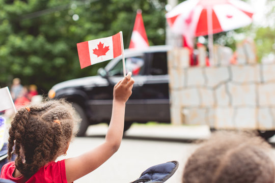 Portrait of child happily waving a Canadian flag at a Canada day parade
