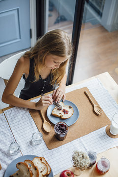 Young girl spread jam on bread