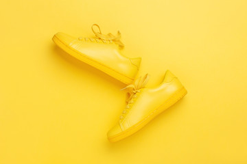 Pair of yellow shoes on yellow background. Trendy summer color, monochrome image with copy space. Hipster concept.