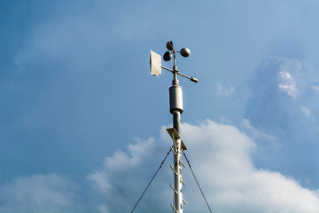 Professional wind weather vane and cloudy dramatic blue sky in weather station. Meteorology concept.  Automatic weather station for monitoring ambient air pressure, humidity, wind speed and direct