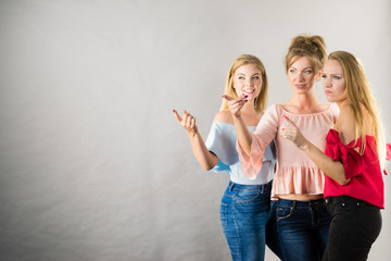 Three fashionable females pointing
