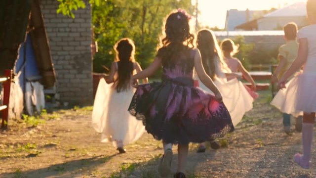 Beautiful little girls in princess dresses run away at sunset.