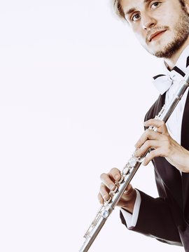 Male flutist wearing tailcoat holds flute