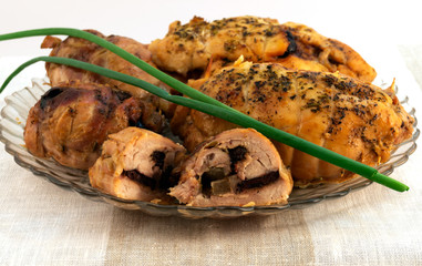 Meat baked rolls with a brown crust, laid on a glass plate with a green onion.