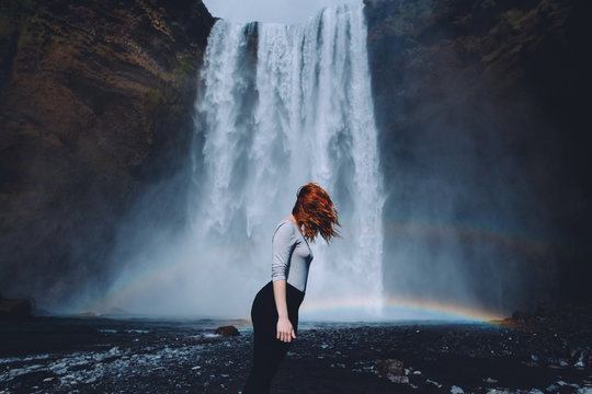 redhead woman posing in front of a waterfall