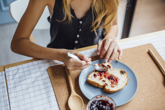 Young girl spread jam on bread