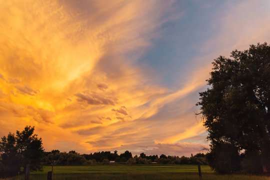 Orange summer sunset over a homestead in Montana.