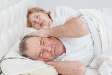 an elderly man covered his ears with his hands so as not to hear the snoring of his wife