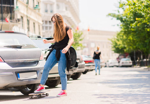 YOUNG WOMAN DOWN THE STREET WITH A LONGBOARD