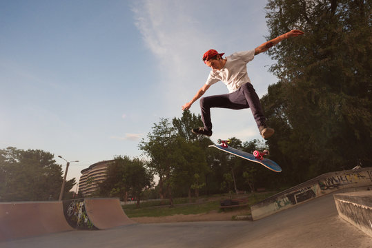 Male teenager performing midair stunts with skateboard in skate park